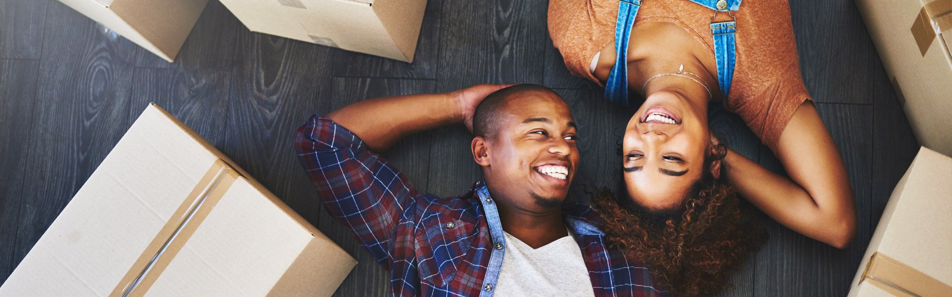 man and woman laying on floor smiling with packaged moving boxes around them