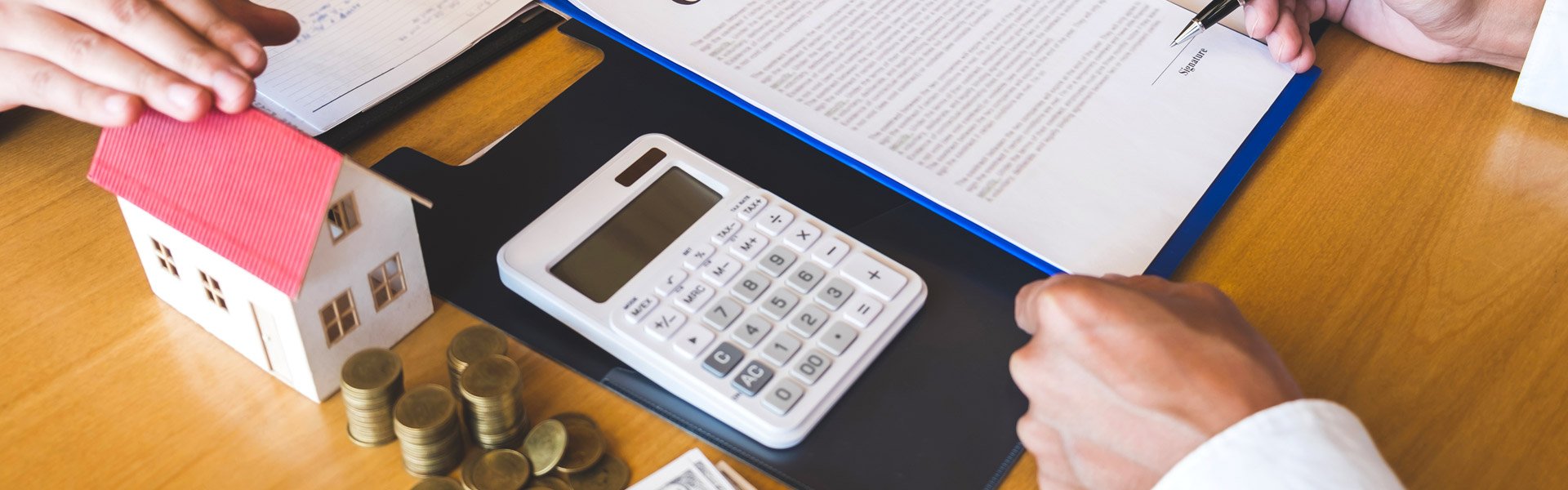 calculator, coins, and a small model home on a desk