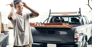 Contractor standing in front of pickup truck with plywood in the back