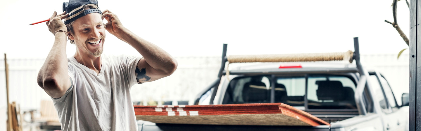 Contractor standing in front of pickup truck with plywood in the back