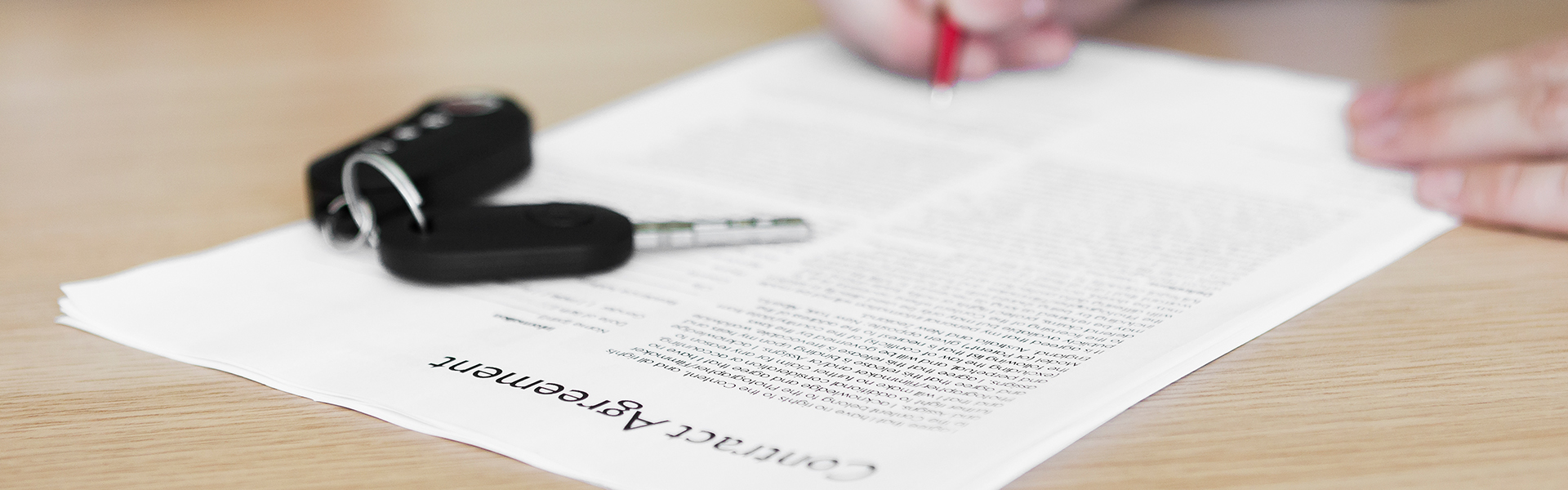 contract being signed with a car key on top