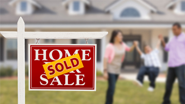 Home for Sale Sign with a Sold Sticker and a Young Family in the Background