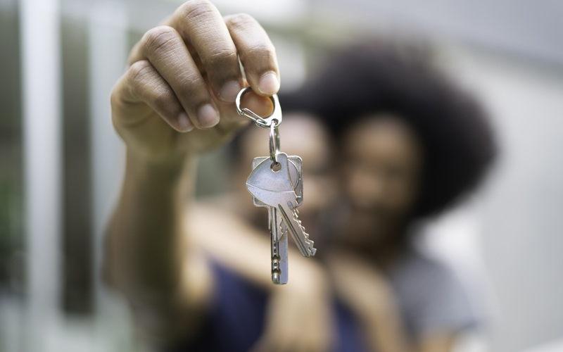 House keys in foreground held by blurred couple in background