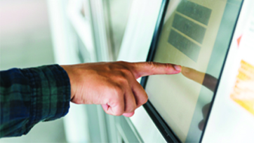 Photo of a hand touching the screen of a new Orange County's Credit Union ATM