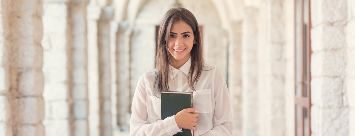 Smiling college student holding textbook