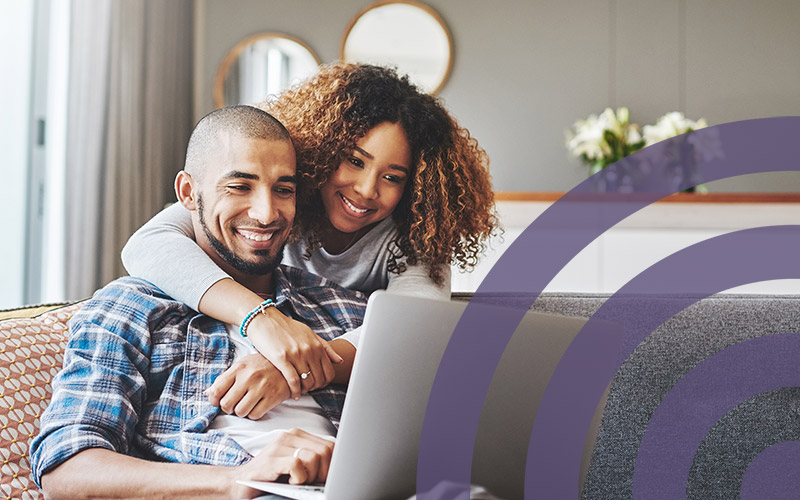 couple smiling down at open laptop