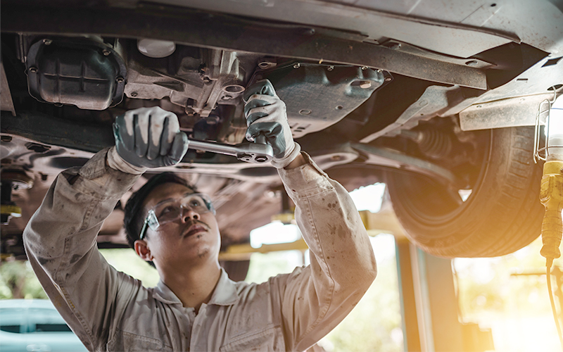 Auto mechanic working underneath a vehicle