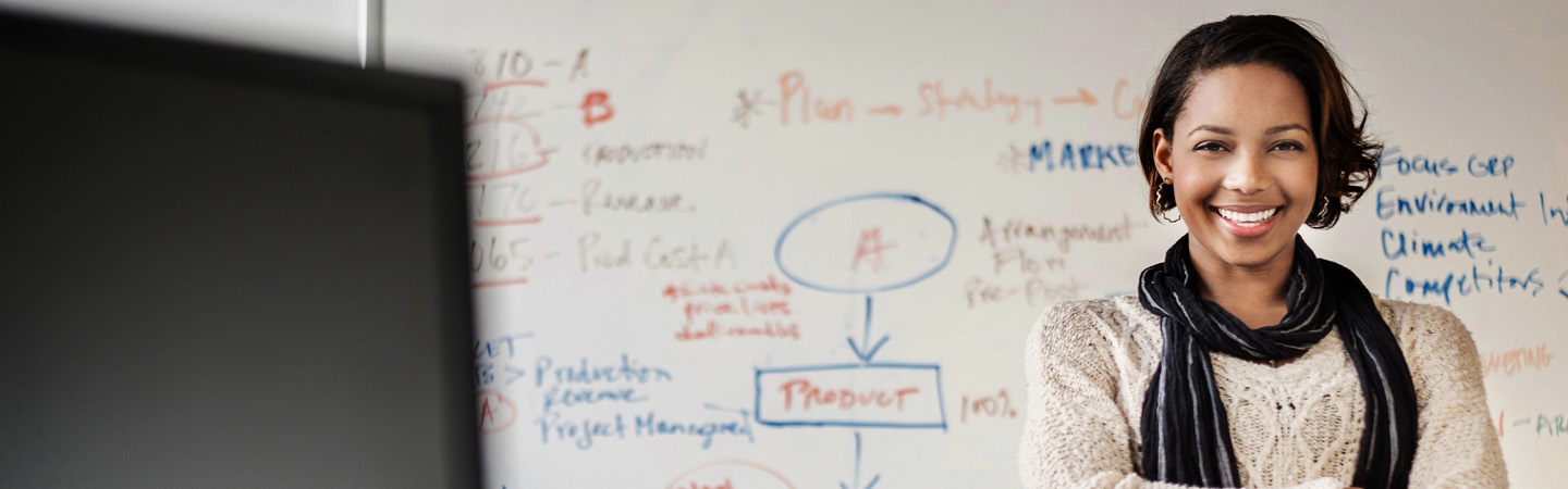 Female professional standing in front of a marked up whiteboard