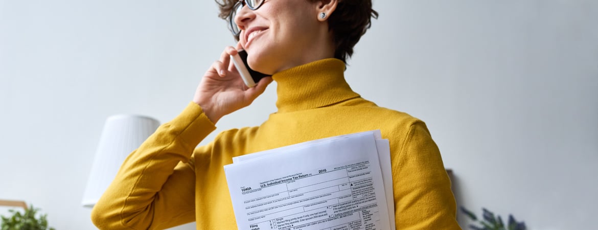 Person holding tax documents while talking on phone