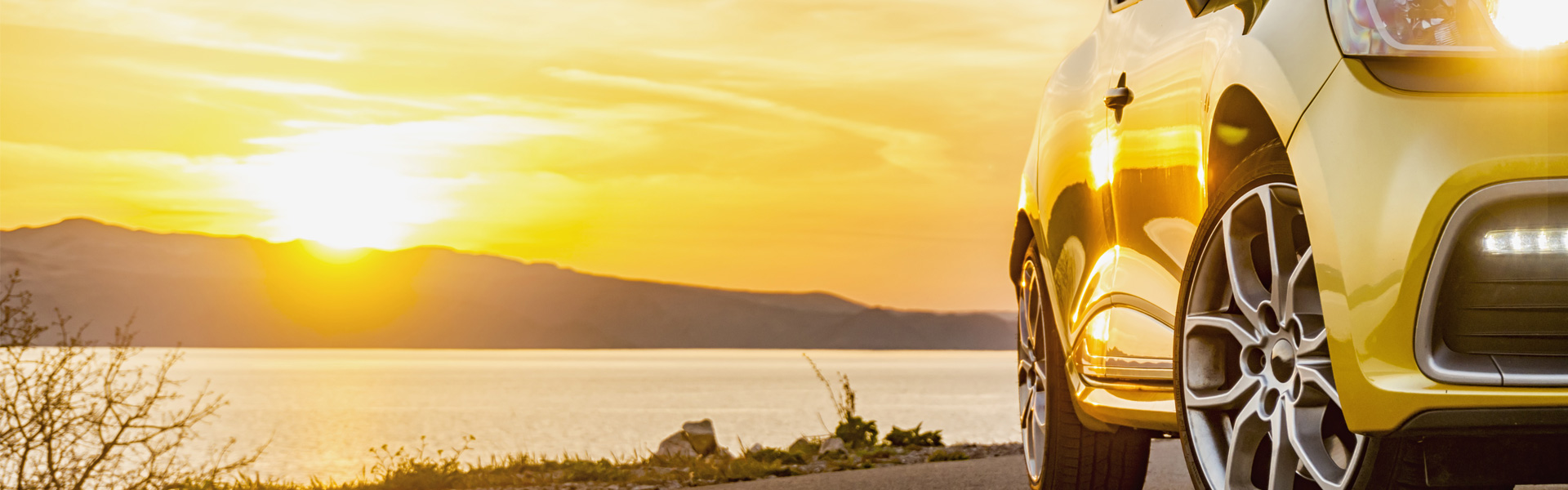 car parked in front of lake at sunset