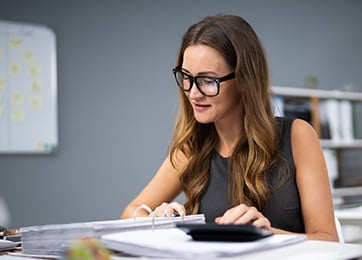 Woman reviewing documents with calculator