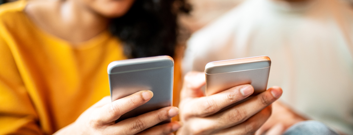 Two friends holding their phones next to each other while making a mobile app payment