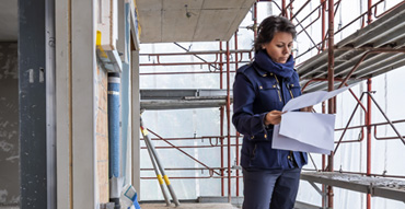 Woman reviewing blueprints while on construction site