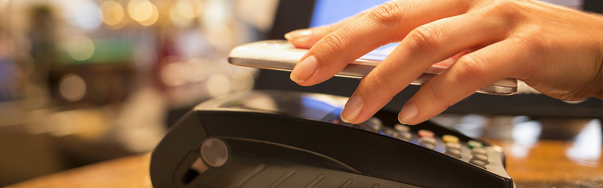 Hand holding phone over payment terminal