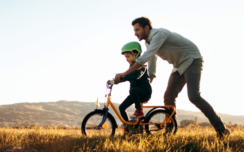 Father pushing son on bike