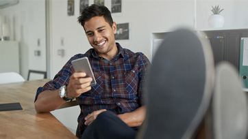 Man relaxing with feet up while looking at his mobile app