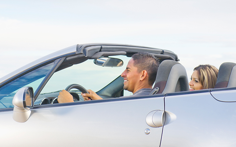 smiling driver and passenger in a convertible car