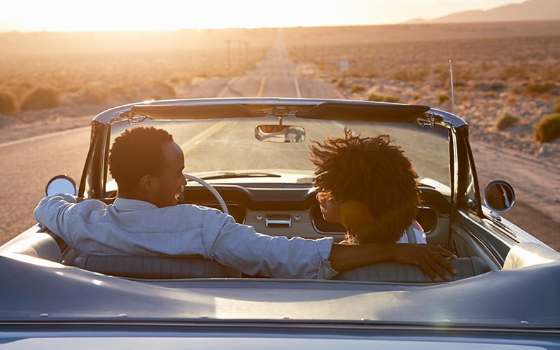 smiling driver and passenger in a convertible car