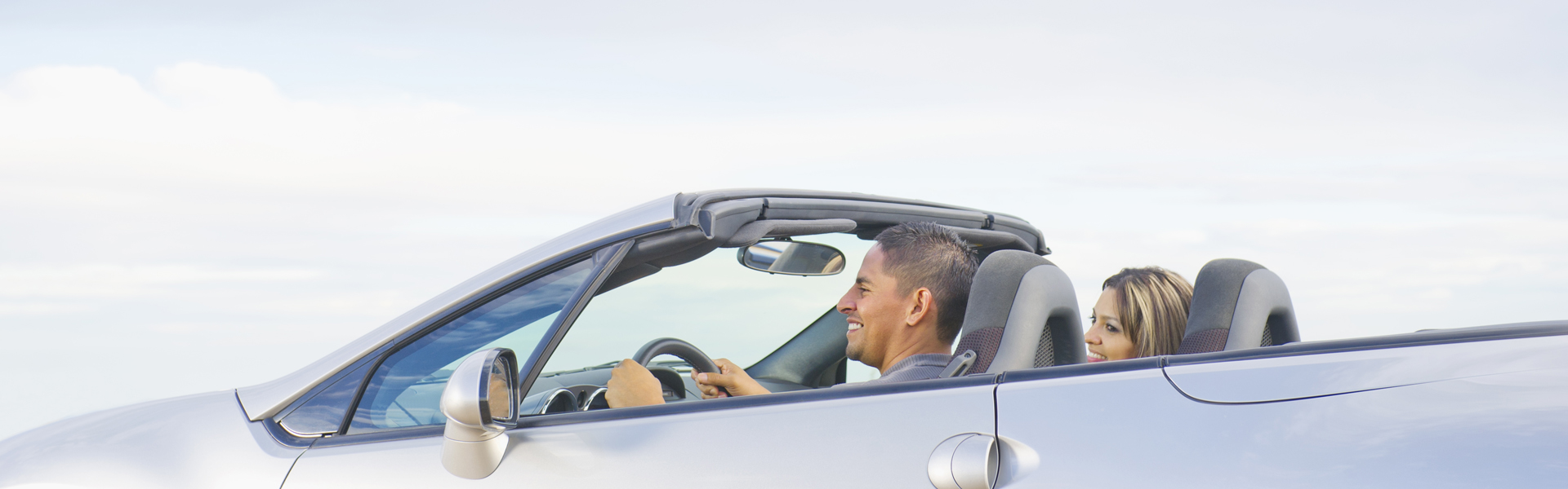 smiling driver and passenger in a convertible car