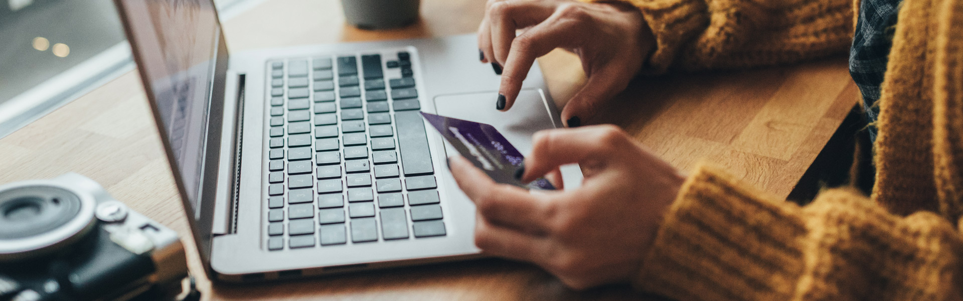 photo of a person's hands typing their credit card information into a laptop