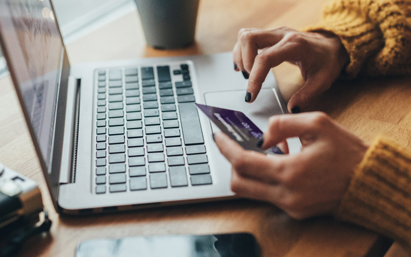 photo of a person's hands typing their credit card information into a laptop