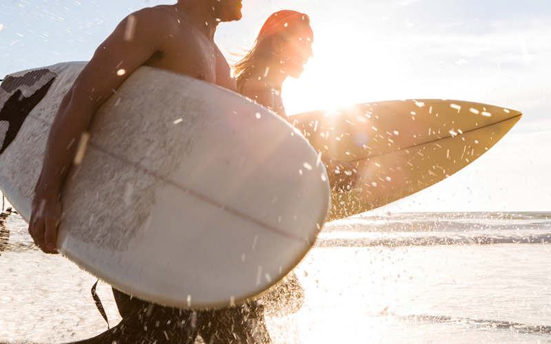 Members running on the beach with surfboards