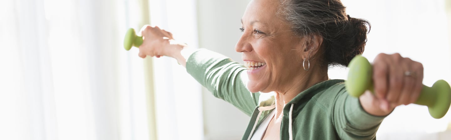 Senior woman holding barbells doing arm exercises