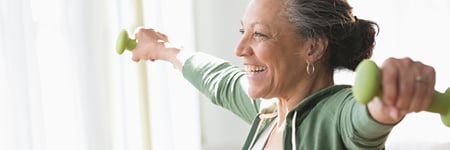 Senior woman holding barbells doing arm exercises