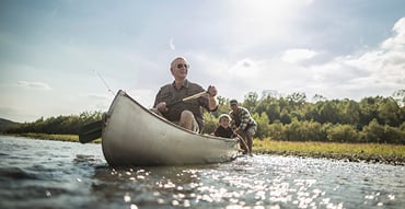 Grandfather, son, and grandson on canoe in lake
