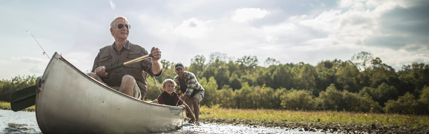 Grandfather, son, and grandson on canoe in lake