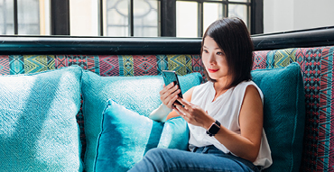Woman sitting on sofa while looking at mobile phone