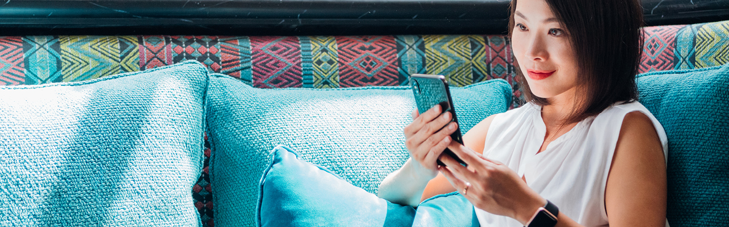Woman sitting on sofa while looking at mobile phone