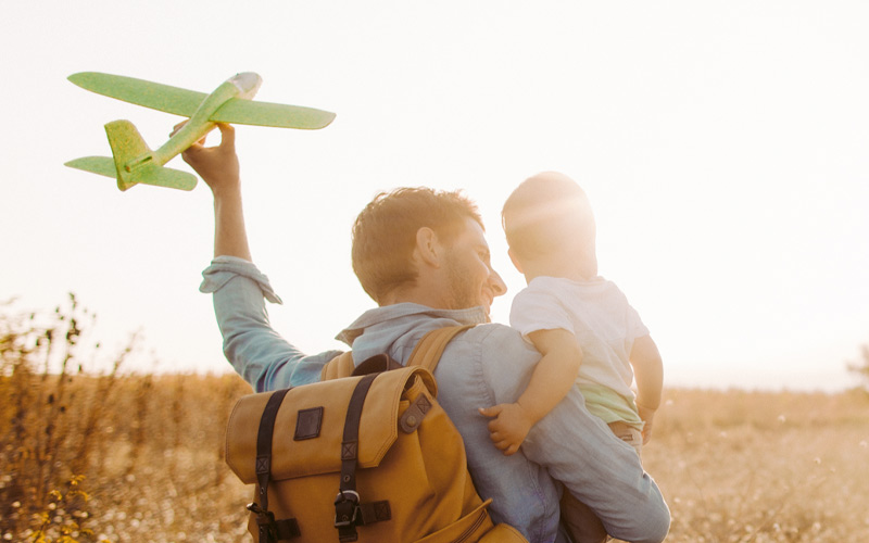 Dad and son in park holding model airplane