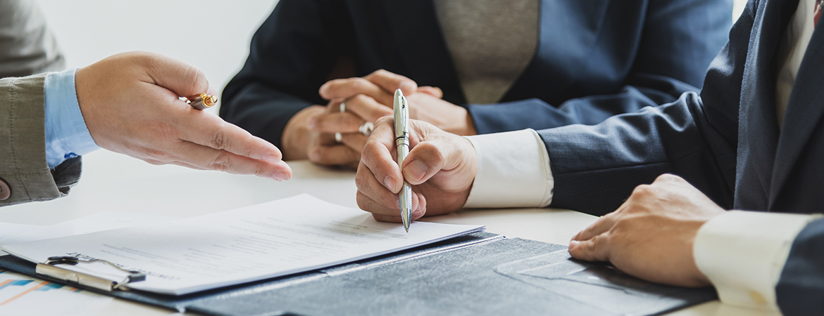 Business people signing agreements at a table