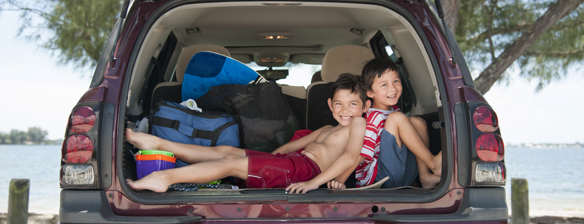 Happy children in back of vehicle on family vacation