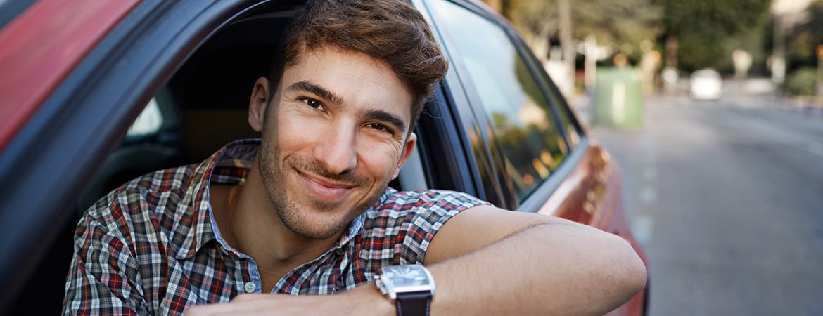 smiling person in driver's seat of vehicle