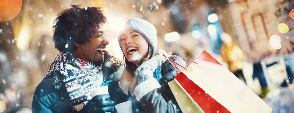Couple laughing in the snow with shopping bags